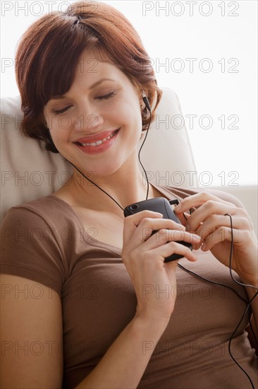 Young woman listening music on armchair. Photo : Rob Lewine