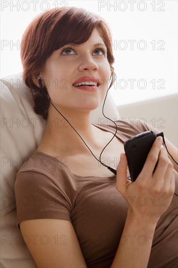 Young woman listening music on armchair. Photo : Rob Lewine