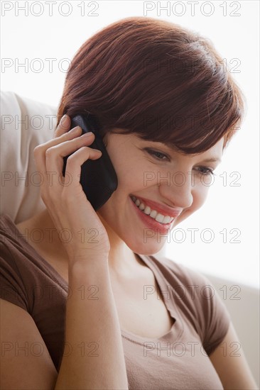 Portrait of young woman sitting on armchair and talking via mobile. Photo : Rob Lewine