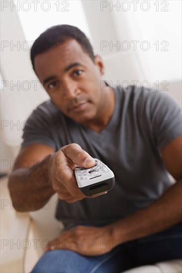 Mature man holding remote control. Photo : Rob Lewine