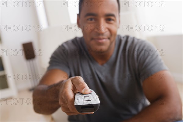 Mature man holding remote control, focus on foreground. Photo : Rob Lewine