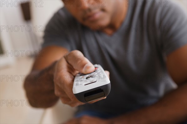 Mature man holding remote control, focus on foreground. Photo : Rob Lewine