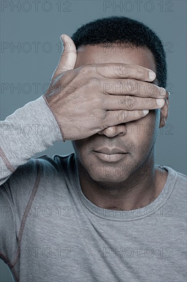 Studio shot of mature man covering eyes. Photo : Rob Lewine