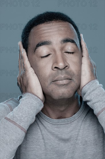 Studio shot of mature man covering ears. Photo : Rob Lewine