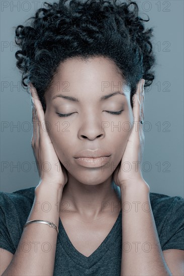 Studio shot of young woman with hands covering ears. Photo : Rob Lewine