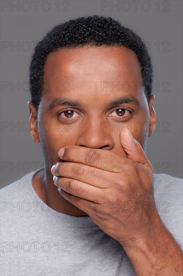 Studio shot of mid adult man covering lips. Photo : Rob Lewine