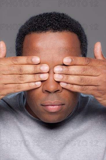 Studio shot of mid adult man covering eyes. Photo : Rob Lewine