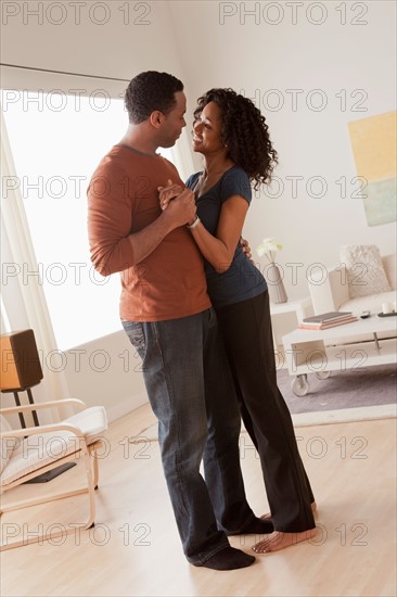 Mid adult couple dancing at home. Photo : Rob Lewine