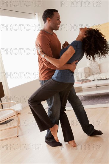 Mid adult couple dancing at home. Photo : Rob Lewine