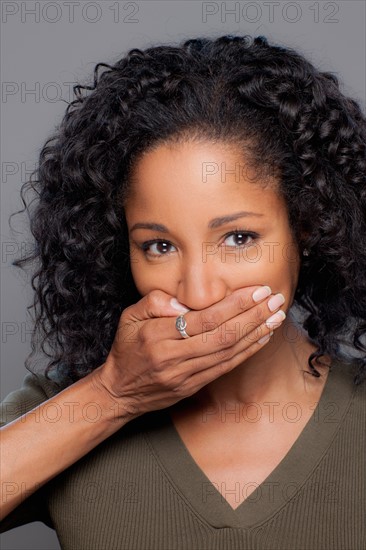 Studio shot of mid adult woman covering lips. Photo : Rob Lewine