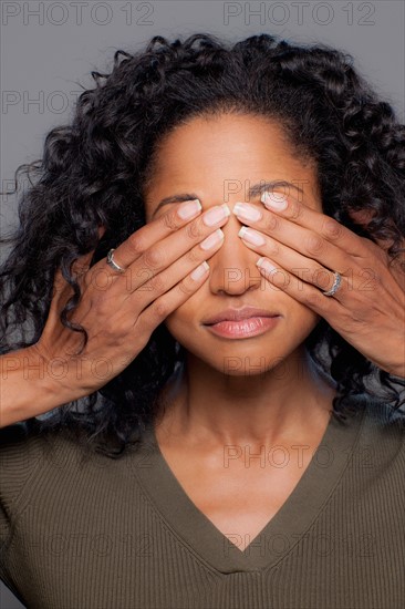 Studio shot of mid adult woman covering eyes. Photo : Rob Lewine