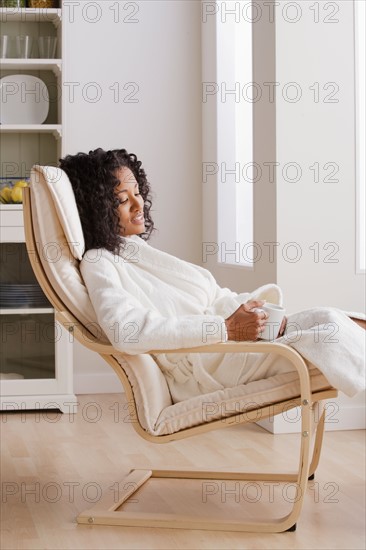 Woman drinking coffee in armchair in morning. Photo : Rob Lewine