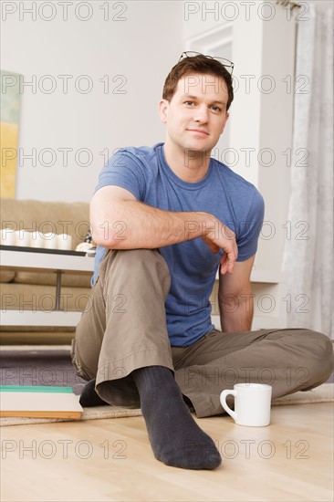 Portrait of smiling mid adult man sitting on floor. Photo : Rob Lewine