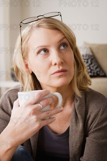 Mid adult woman drinking coffee and looking away. Photo : Rob Lewine