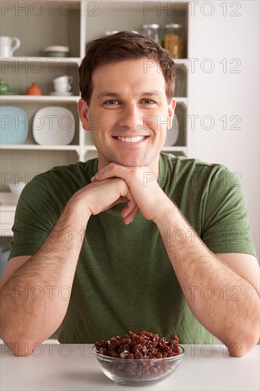 Portrait of mid adult man with bowl of raisins. Photo : Rob Lewine