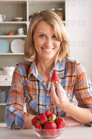 Portrait of mid adult woman with bowl of strawberries. Photo : Rob Lewine