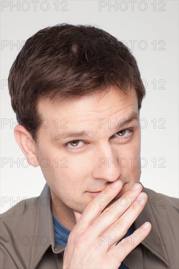 Studio shot of mid adult man covering lips. Photo : Rob Lewine