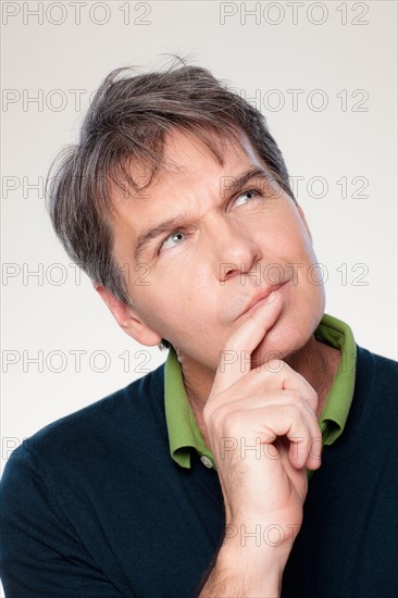 Studio portrait of mature man with hand on chin. Photo : Rob Lewine