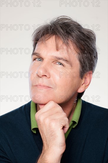 Studio portrait of mature man with hand on chin. Photo : Rob Lewine