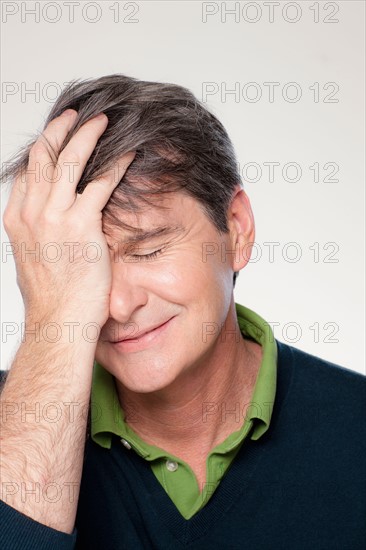 Studio portrait of mature man with head in hands. Photo : Rob Lewine