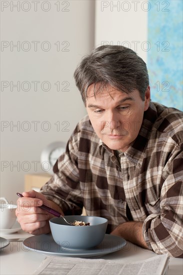 Man eating breakfast and reading newspaper. Photo : Rob Lewine