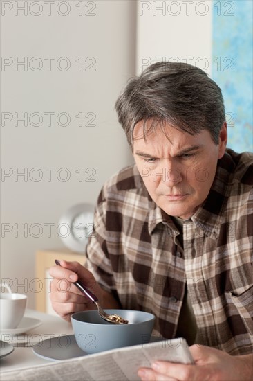 Man eating breakfast and reading newspaper. Photo : Rob Lewine