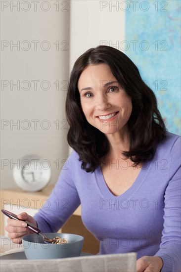 Woman eating breakfast and reading newspaper. Photo : Rob Lewine