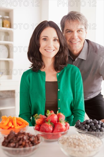 Portrait of mature couple with snacks on table. Photo : Rob Lewine