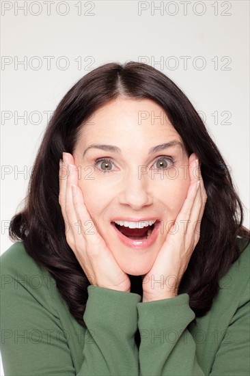Studio portrait of mature woman with head in hands. Photo : Rob Lewine