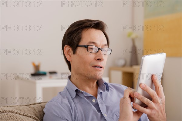 Man reading e-book at home. Photo : Rob Lewine