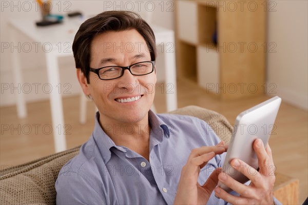 Portrait of man reading e-book at home. Photo : Rob Lewine