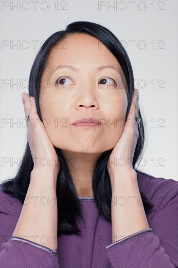 Studio portrait of mature woman covering ears. Photo : Rob Lewine