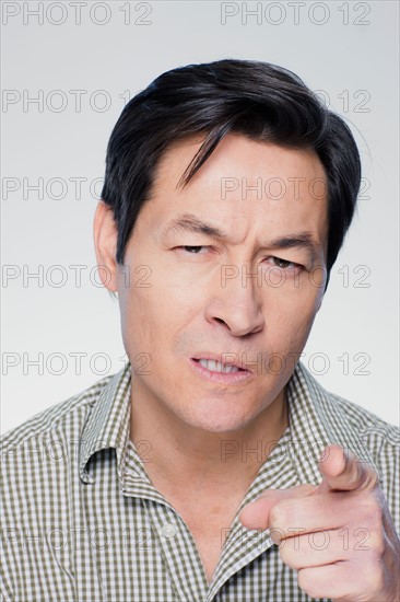 Studio portrait of mature man pointing finger. Photo : Rob Lewine