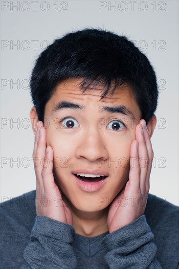 Studio portrait of young man with head in hands. Photo : Rob Lewine