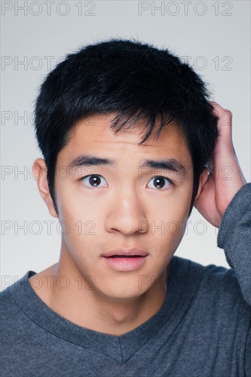 Studio portrait of young man scratching head. Photo : Rob Lewine