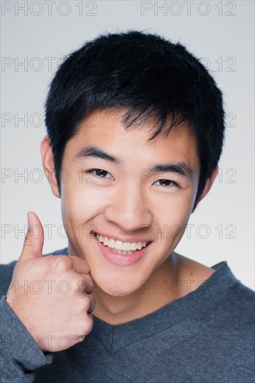 Studio portrait of young man showing thumbs up sign. Photo : Rob Lewine