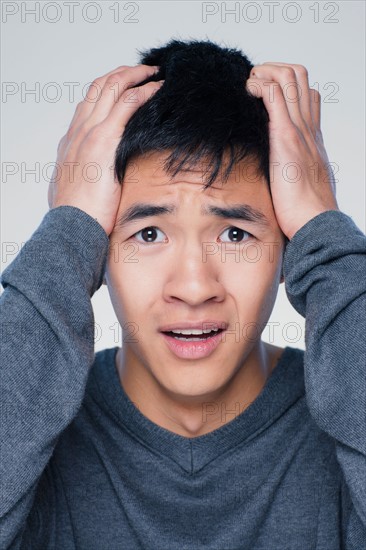 Studio portrait of young man with head in hands. Photo : Rob Lewine