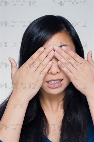 Studio portrait of young woman covering eyes. Photo : Rob Lewine
