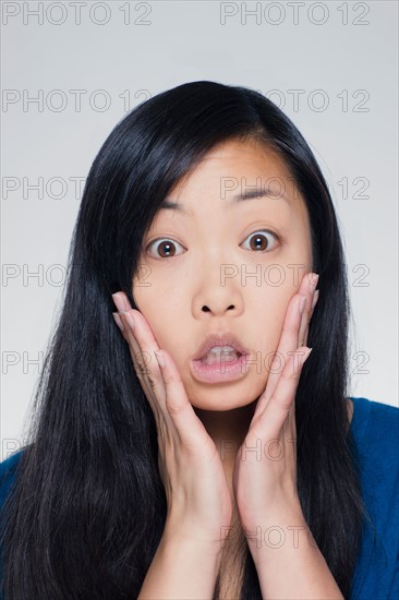 Studio portrait of young woman with head in hands. Photo : Rob Lewine