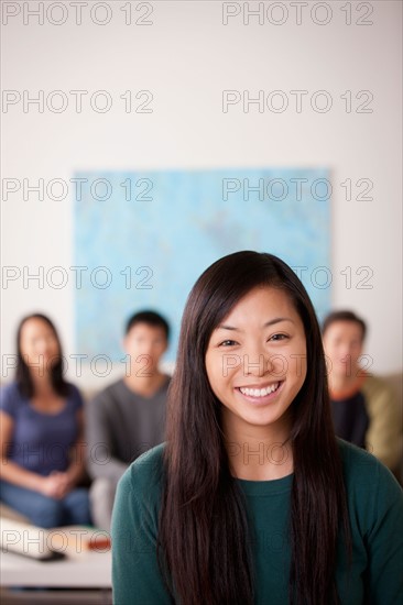 Portrait of young woman with family in background. Photo : Rob Lewine