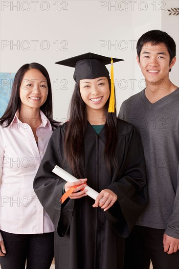 Portrait of young woman in graduation gown with mother and brother. Photo : Rob Lewine