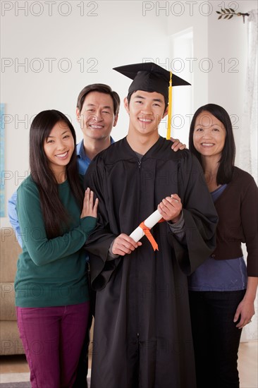 Portrait of young man in graduation gown with family. Photo : Rob Lewine