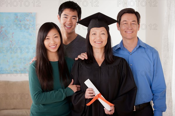 Portrait of young man in graduation gown with family. Photo : Rob Lewine