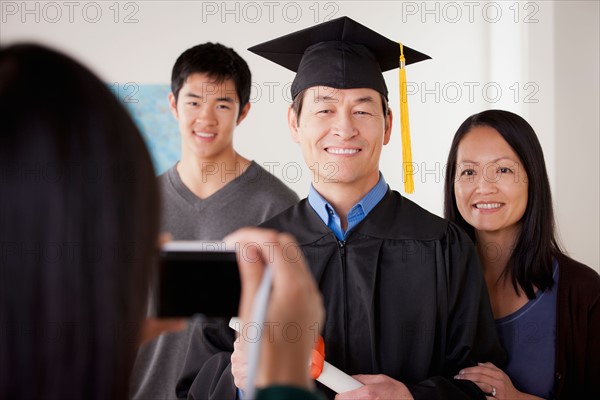 Portrait of mature man in graduation gown with family. Photo : Rob Lewine