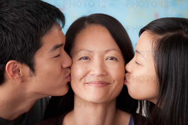 Smiling mother kissed by her children. Photo : Rob Lewine