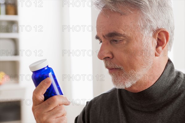 Senior men reading label on medicine bottle. Photo : Rob Lewine