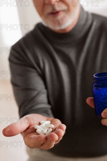 Senior men holding pills. Photo : Rob Lewine