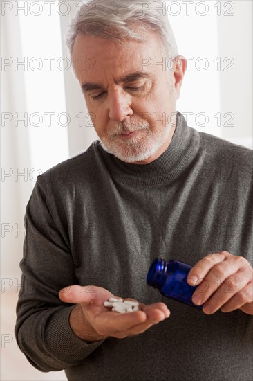 Senior men holding pills. Photo : Rob Lewine