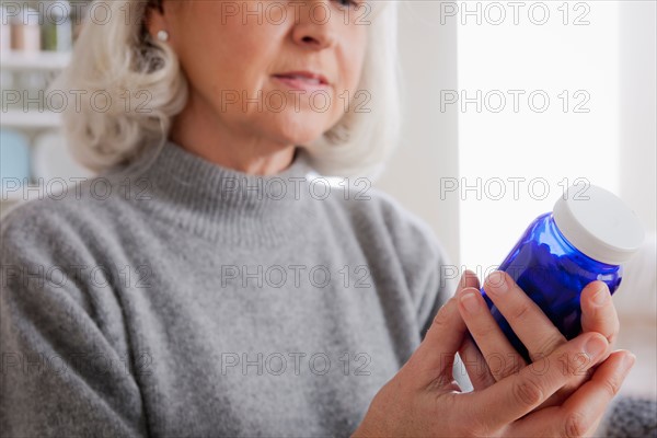 Senior women reading label on medicine bottle. Photo : Rob Lewine