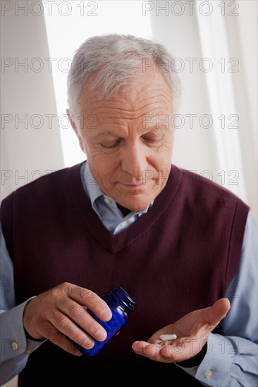 Senior man holding medicine bottle. Photo : Rob Lewine